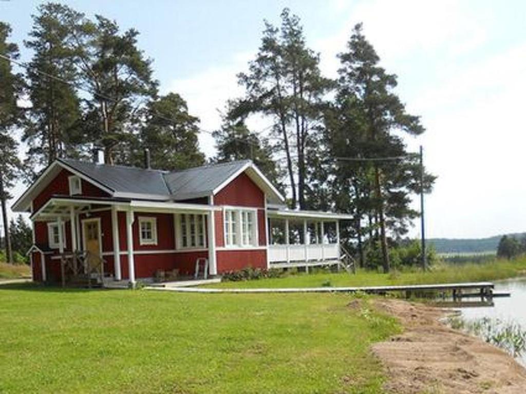 uma casa vermelha sentada ao lado de um lago em Holiday Home Vauvila by Interhome em Kyynämäki