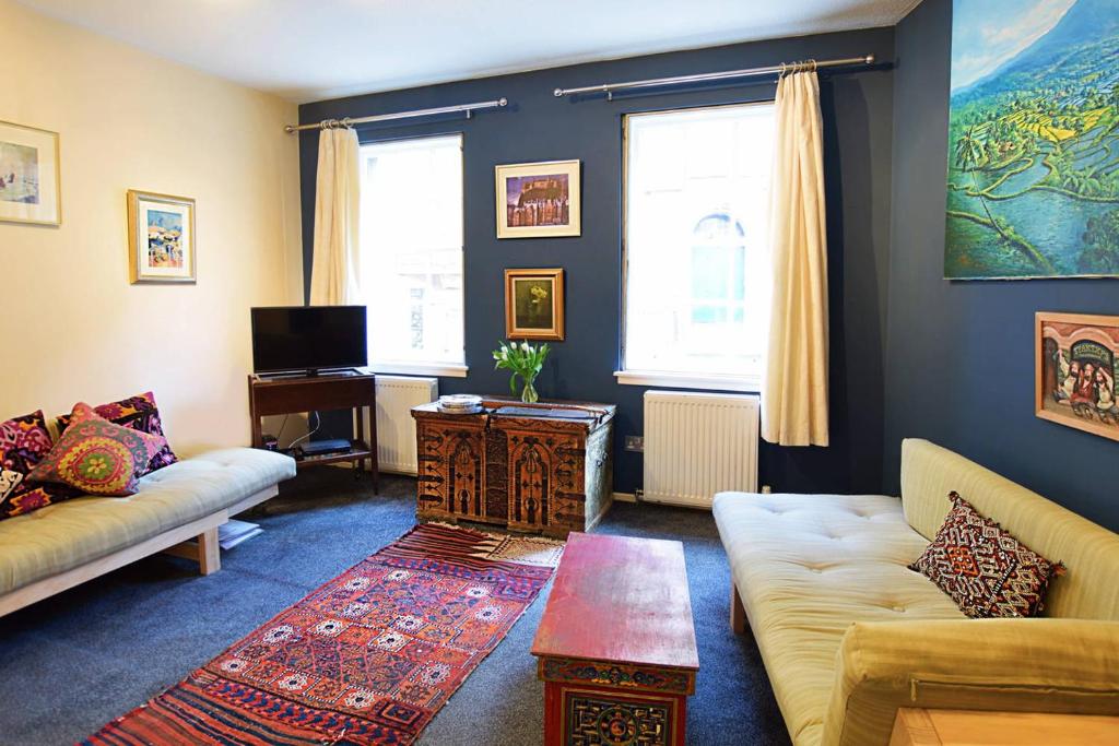 ein Wohnzimmer mit einem Sofa und einem Tisch in der Unterkunft ALTIDO Bohemian Writers Retreat in Heart of The Old Town in Edinburgh