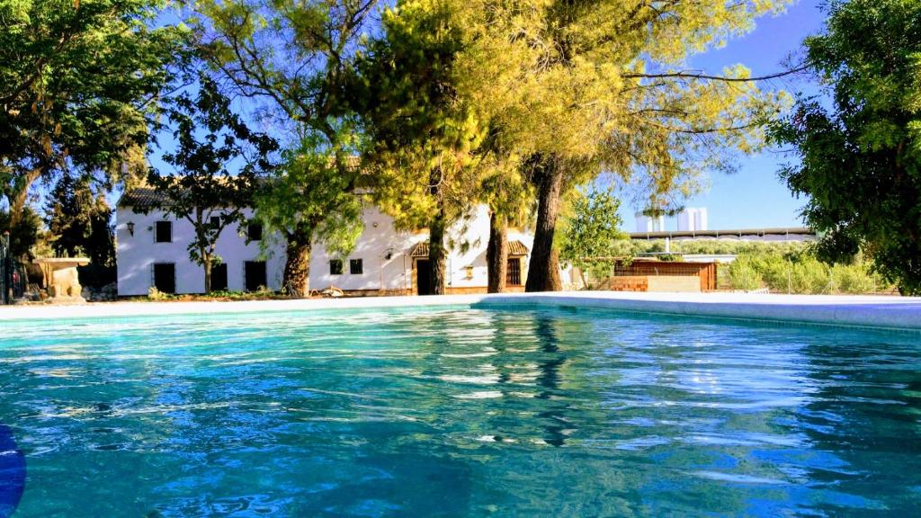 a swimming pool with trees and a house in the background at VTAR Don Benito, su casa rural en Gilena in Gilena