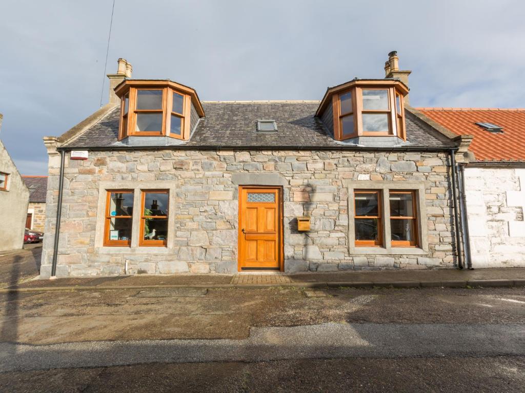 a stone house with a orange door and windows at Cullen 117 Seatown With Sea Views in Cullen