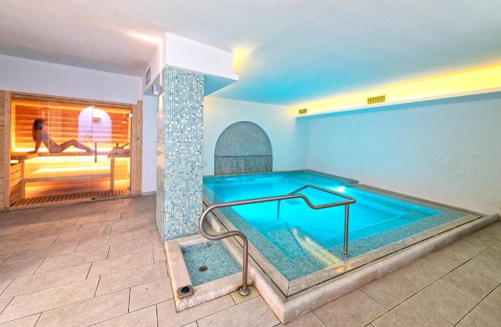 a swimming pool in a house with a woman in the background at Family Spa Hotel Le Canne in Ischia