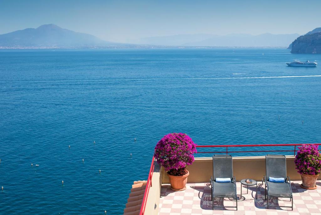 a balcony with chairs and flowers on the water at Hotel Minerva in Sorrento