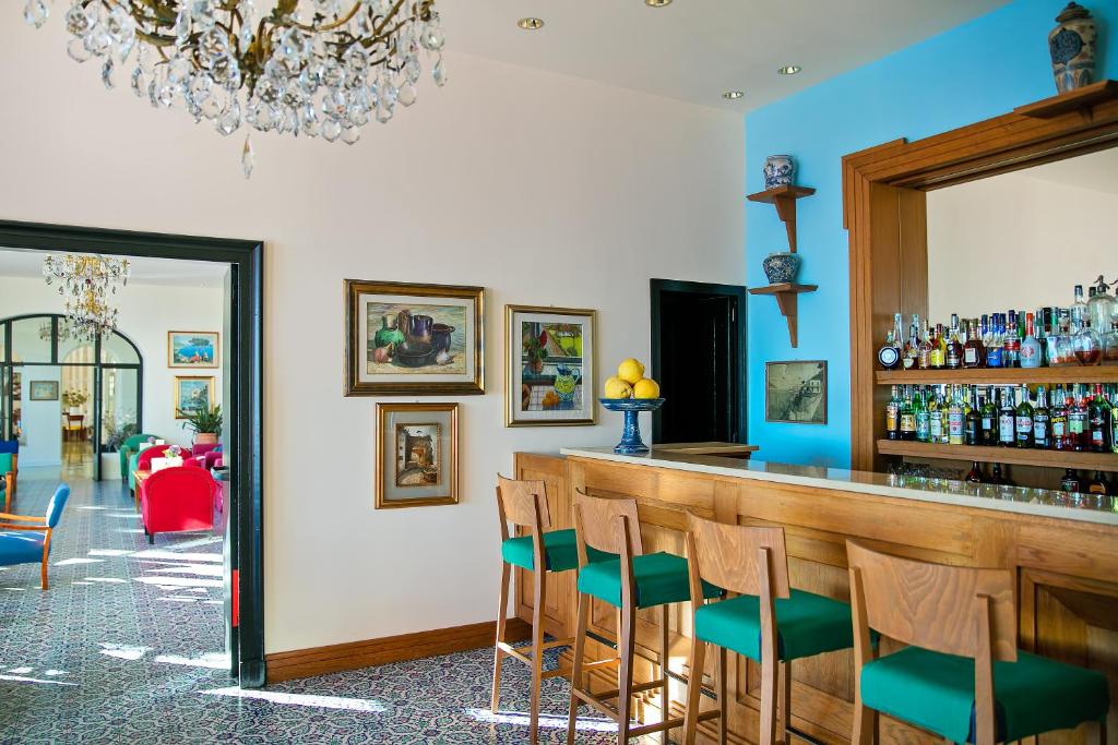 a bar with blue walls and wooden chairs at Hotel Minerva in Sorrento
