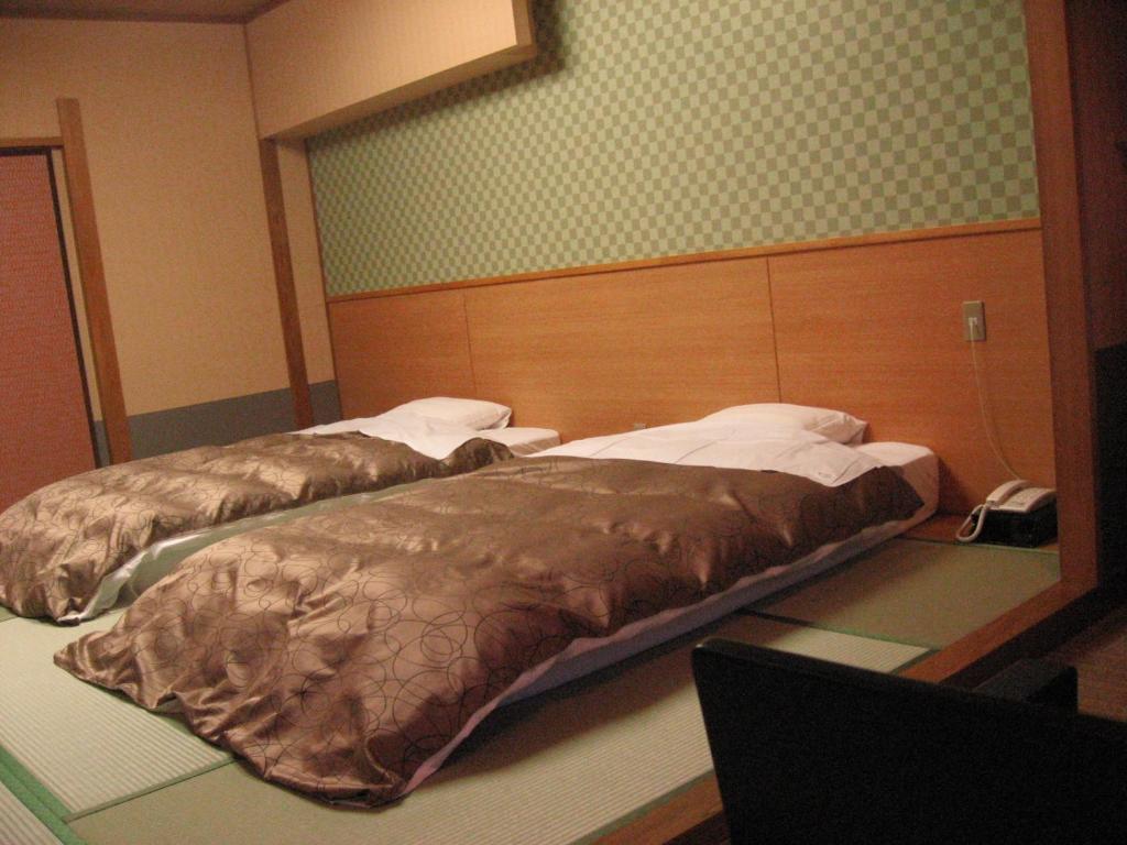 two beds in a hotel room with avertisement at Hotel Ootaki in Nikko