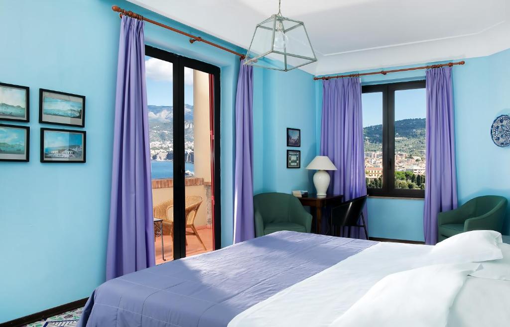 sypialnia z niebieskimi ścianami i łóżkiem z fioletowymi zasłonami w obiekcie Hotel Minerva w Sorrento
