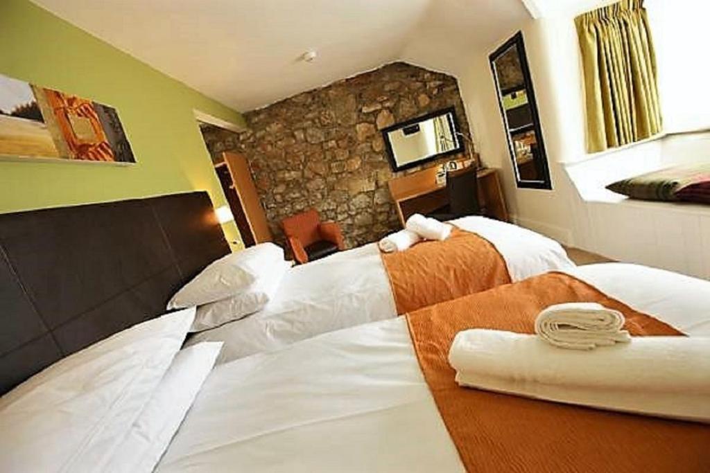a hotel room with two beds and a stone wall at Rose And Crown in Porthcawl