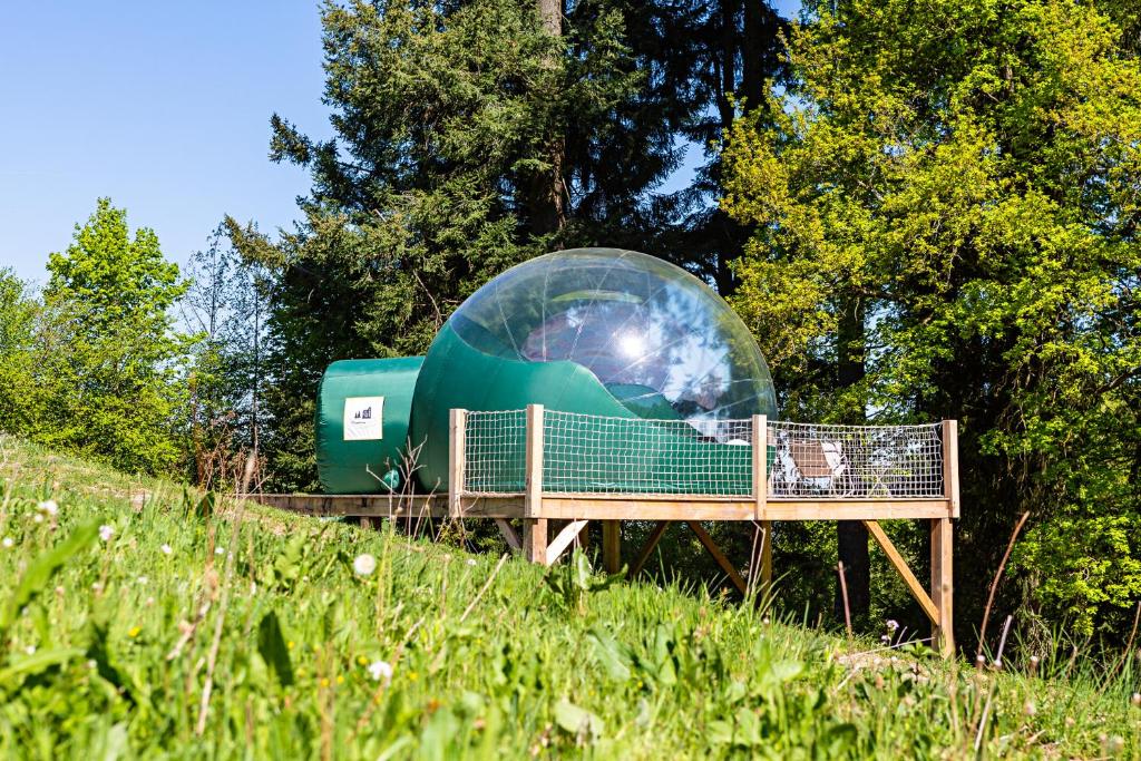 un dôme en verre assis au-dessus d'un banc en bois dans l'établissement Monchateau étoilé, hébergement insolite avec Spa, à Merlas