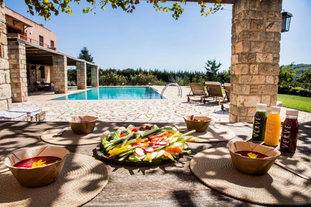 uma mesa com uma bandeja de frutas e legumes ao lado de uma piscina em Mediterra retreat em Kapandrítion
