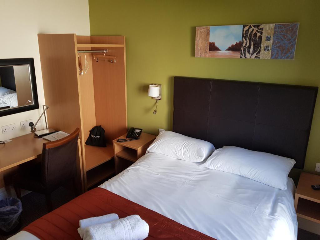 a hotel room with a bed and a desk and a mirror at Rose And Crown in Porthcawl