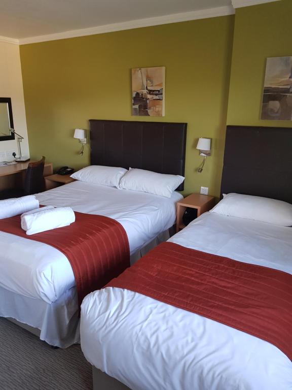 a hotel room with two beds with red and white sheets at Rose And Crown in Porthcawl