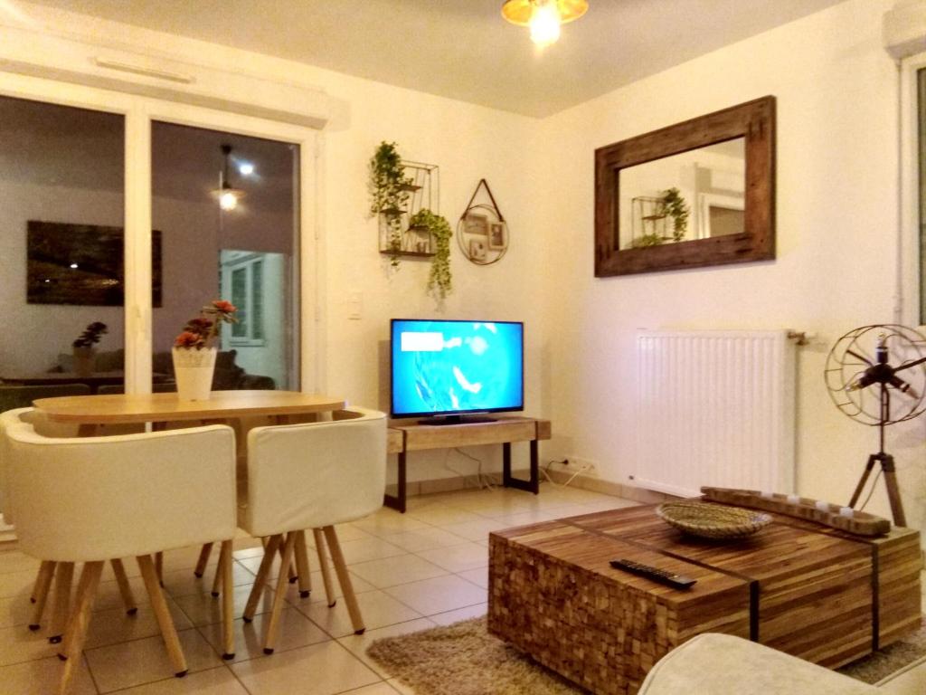 a living room with a television and a table and chairs at Chic apart terrace garden parking in Cergy