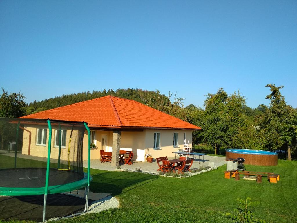 Holiday House Adrelot في Heřmaničky: منزل به سقف برتقالي مع ترامبولين