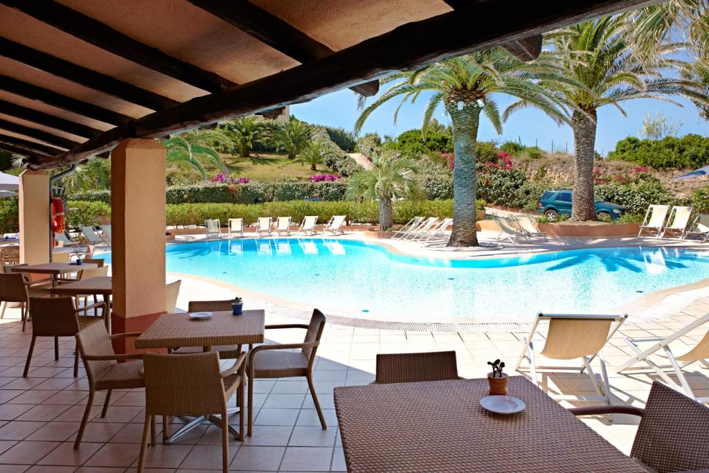 a pool at a resort with tables and chairs at Hotel Corallaro in Santa Teresa Gallura