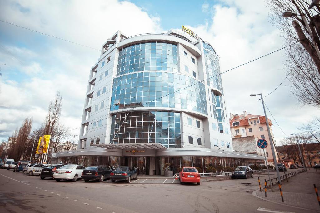 un grand bâtiment avec des voitures garées dans un parking dans l'établissement Hotel Marton Palace, à Kaliningrad