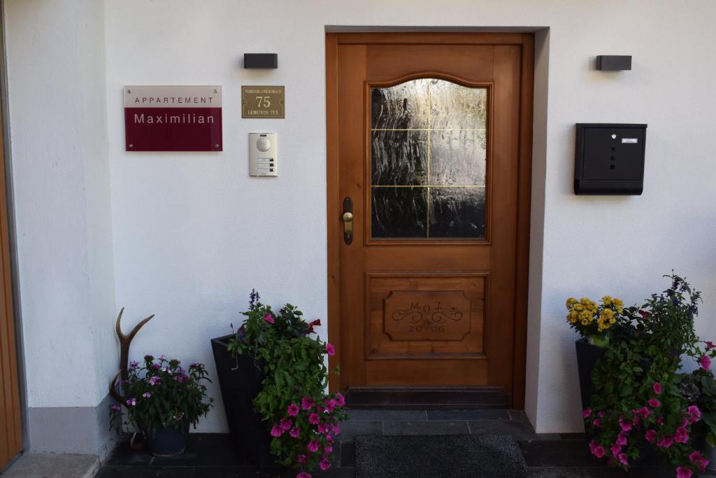 eine Holztür in einem weißen Gebäude mit Blumen in der Unterkunft Appartement Maximilian in Tux