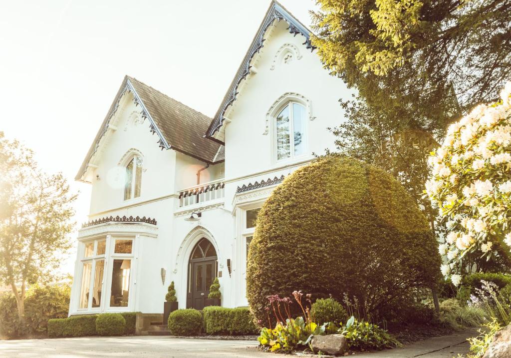 a white house with a large bush in front of it at Didsbury House Hotel in Manchester