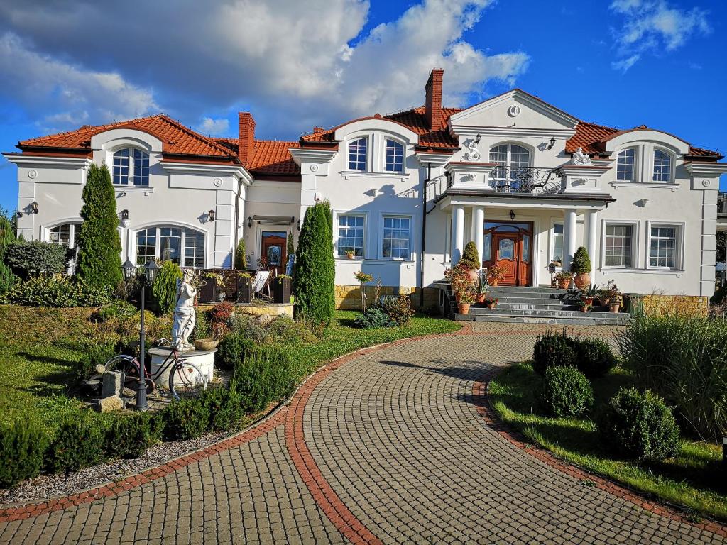 uma grande casa branca com uma entrada de tijolos em Pensjonat Błękitny Anioł em Kiersztanowo