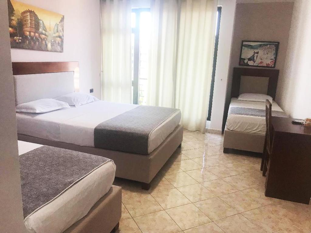 a hotel room with two beds and a desk at Hotel ANTAG in Shëngjin