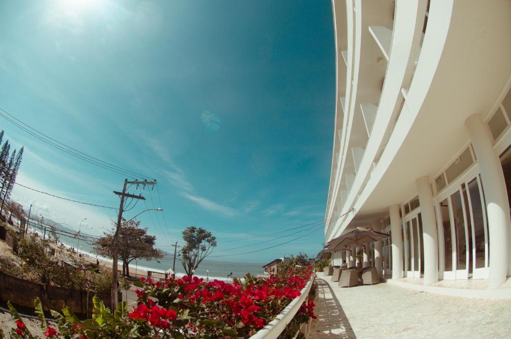 Hotel Marambaia Cabeçudas - frente mar في إيتاجاي: اطلالة على الشاطئ من مبنى عليه زهور