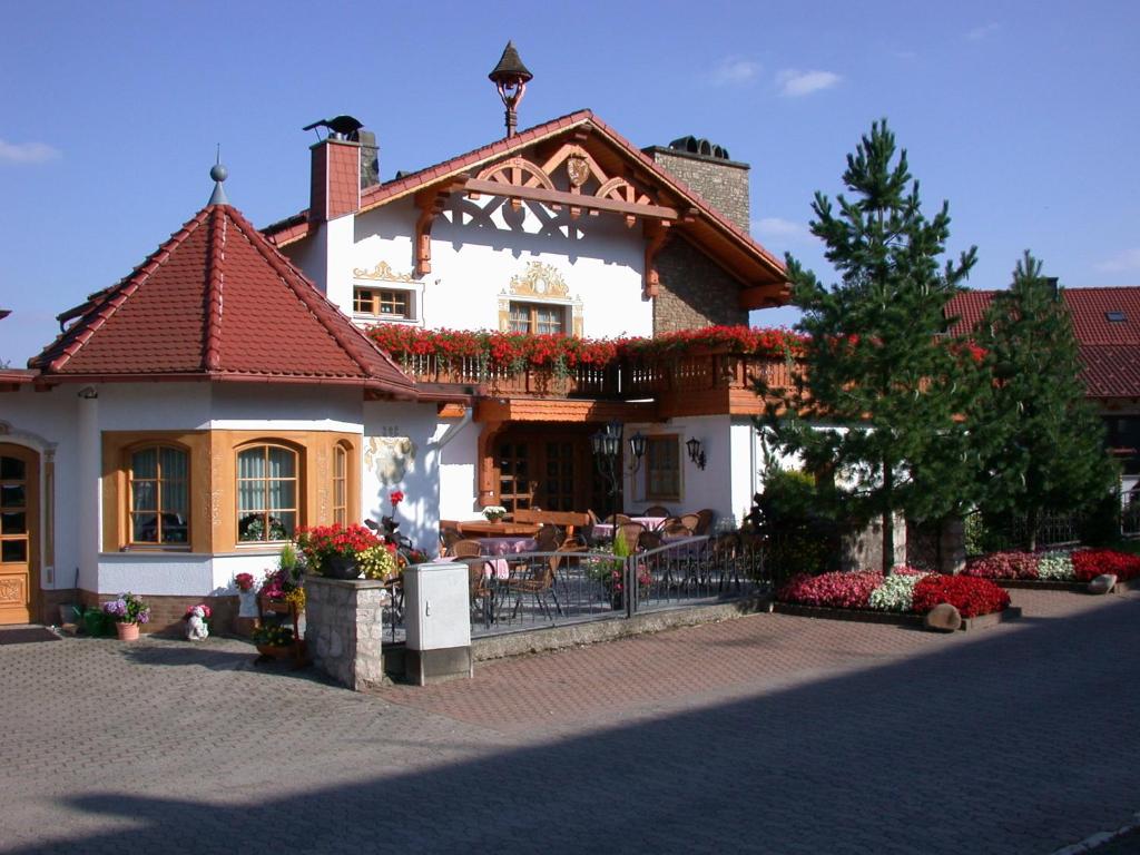 a building with a balcony with flowers on it at Hotel Mühlenberg in Bad Sachsa