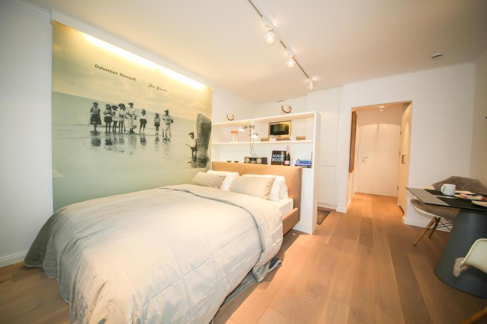 ティメンドルファー・シュトラントにあるFerienwohnung Am Strandの大きなベッド付きのベッドルーム1室、壁に絵画が飾られています。