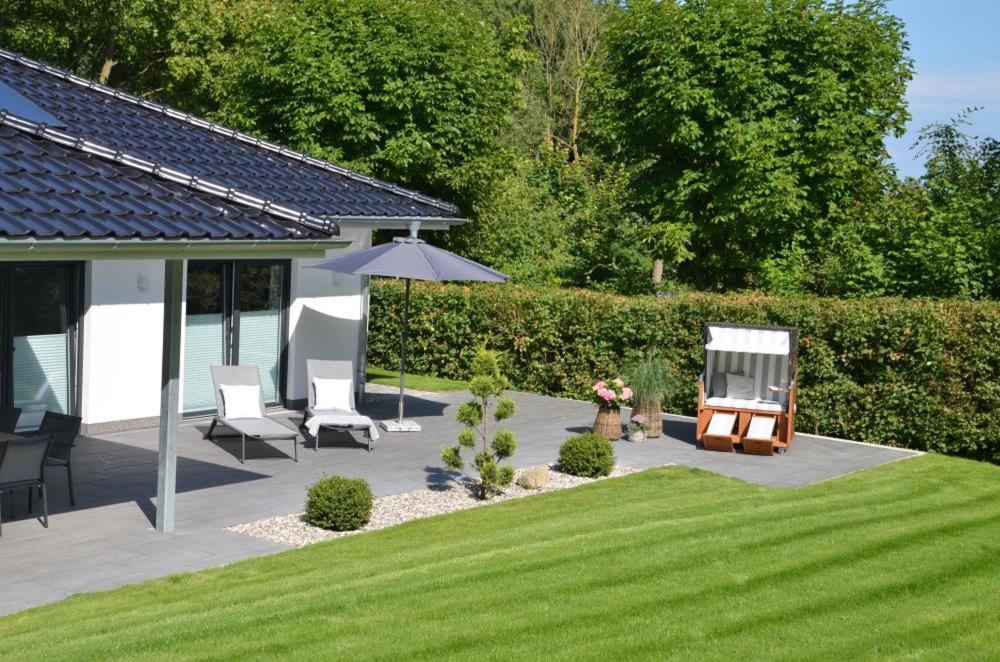 une terrasse avec 2 chaises longues et un parasol dans l'établissement Ferienhaus Beach House Scharbeutz, à Scharbeutz