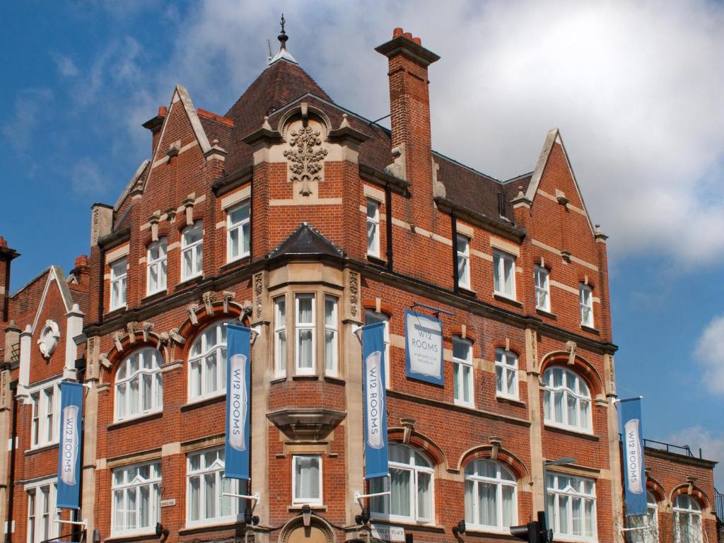 un grand bâtiment en briques rouges avec une tour d'horloge dans l'établissement W12 Rooms, à Londres