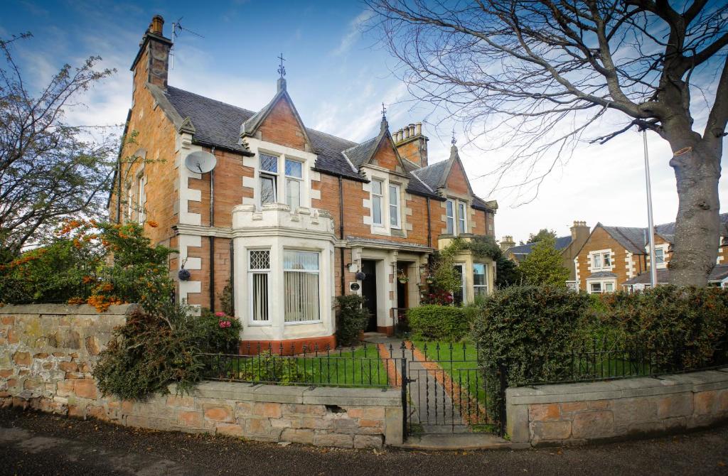 a large brick house with a fence in front of it at Ness House in Inverness