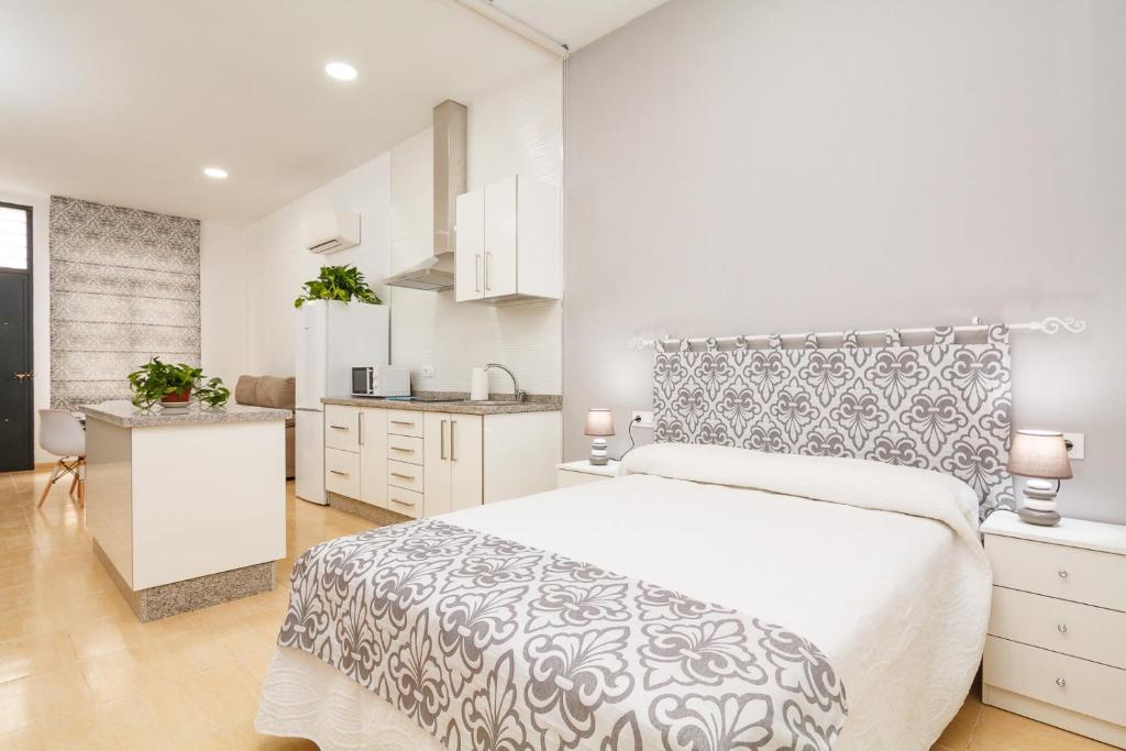 a white bedroom with a large bed and a kitchen at Canadian 2 in Córdoba