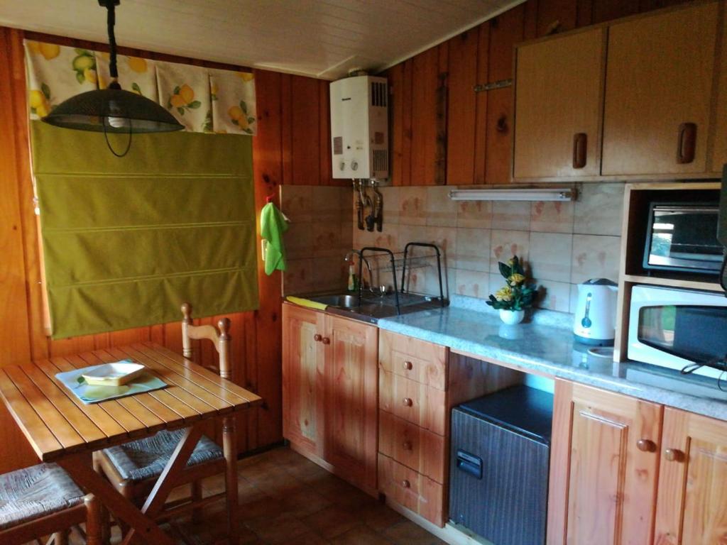 una cocina con armarios de madera y una mesa pequeña. en Torres Del Sur Cabañas & Hostal, en Villarrica