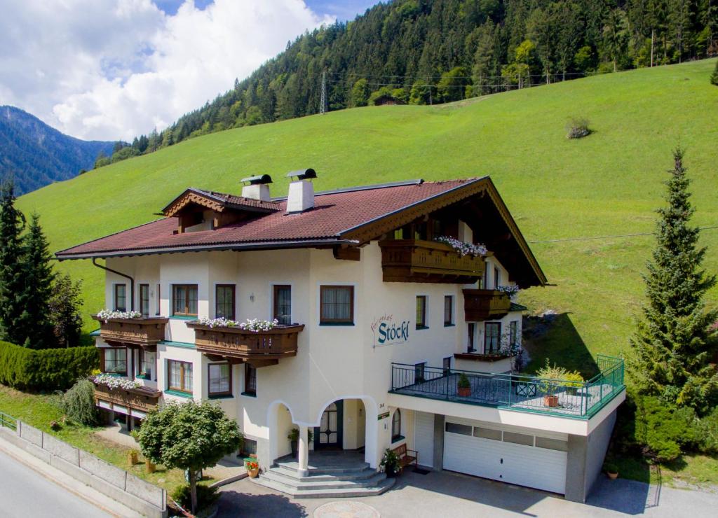 una casa grande con una colina verde en el fondo en Ferienhof Stöckl, en Finkenberg