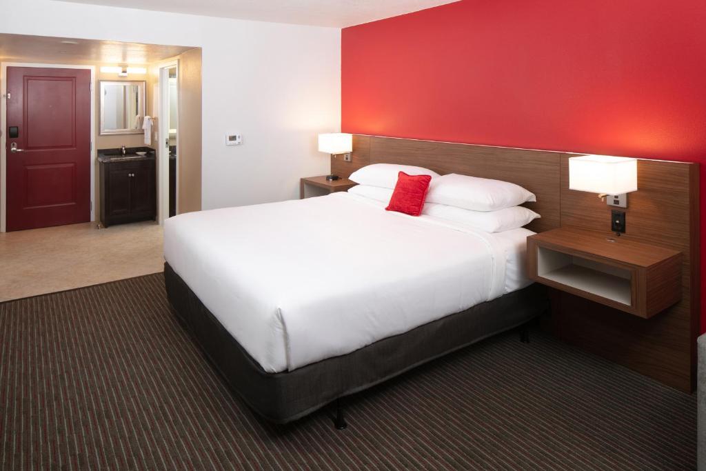 a hotel room with a large bed and a red wall at Red Lion Hotel Orlando Lake Buena Vista South- Near Disney in Kissimmee