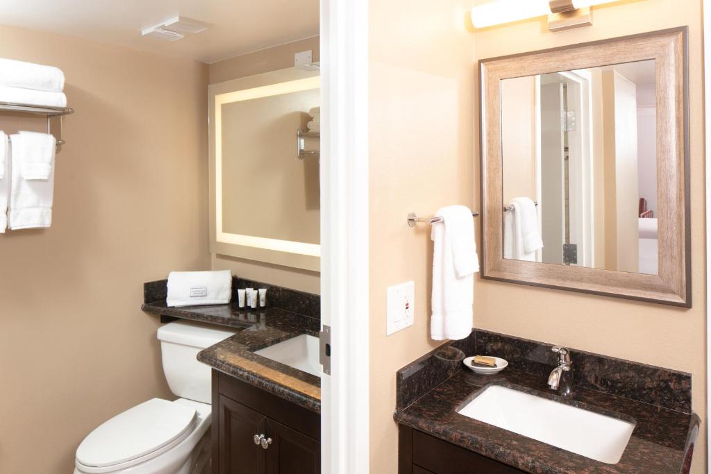 a bathroom with a toilet and a sink and a mirror at Red Lion Hotel Orlando Lake Buena Vista South- Near Disney in Kissimmee