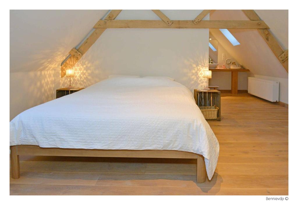 een slaapkamer met een groot bed met witte lakens bij Geetkotmolenhoeve in Lochristi