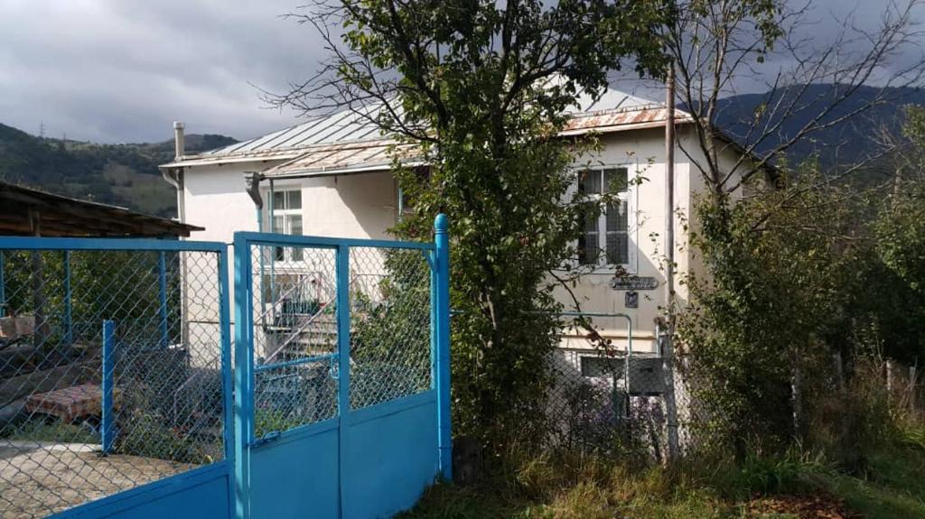 Uma casa branca com uma cerca azul à frente. em Ojakh em Dilijan