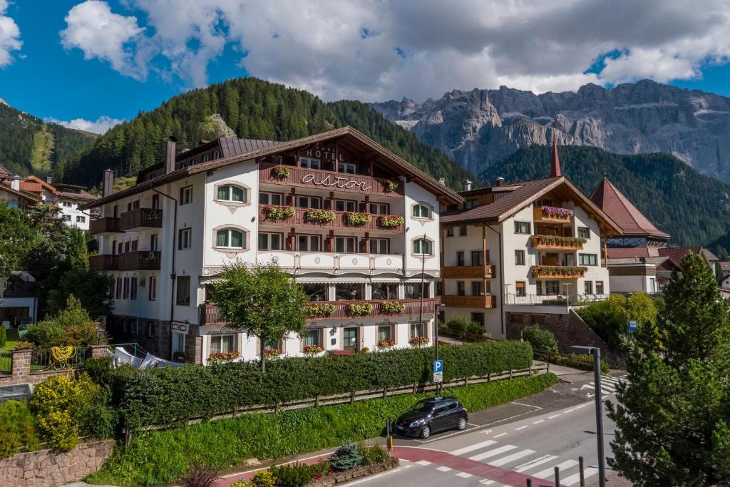 a hotel in the mountains with a road in front at Astor Suites B&B in Selva di Val Gardena