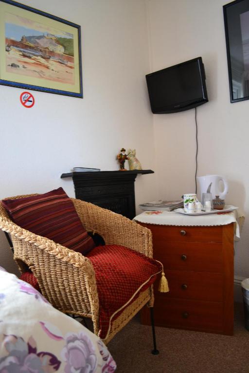 a bedroom with a chair and a dresser with a television at Knightsrest in Burnham on Sea