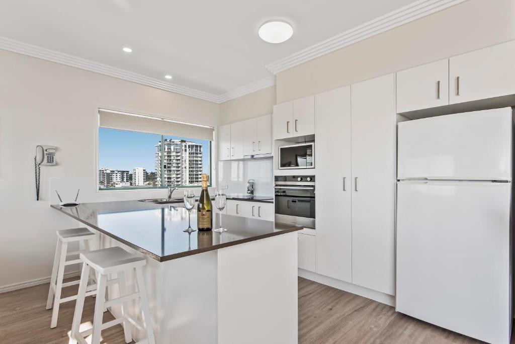 a kitchen with white cabinets and white appliances at Sunshine Towers Boutique Apartments in Maroochydore