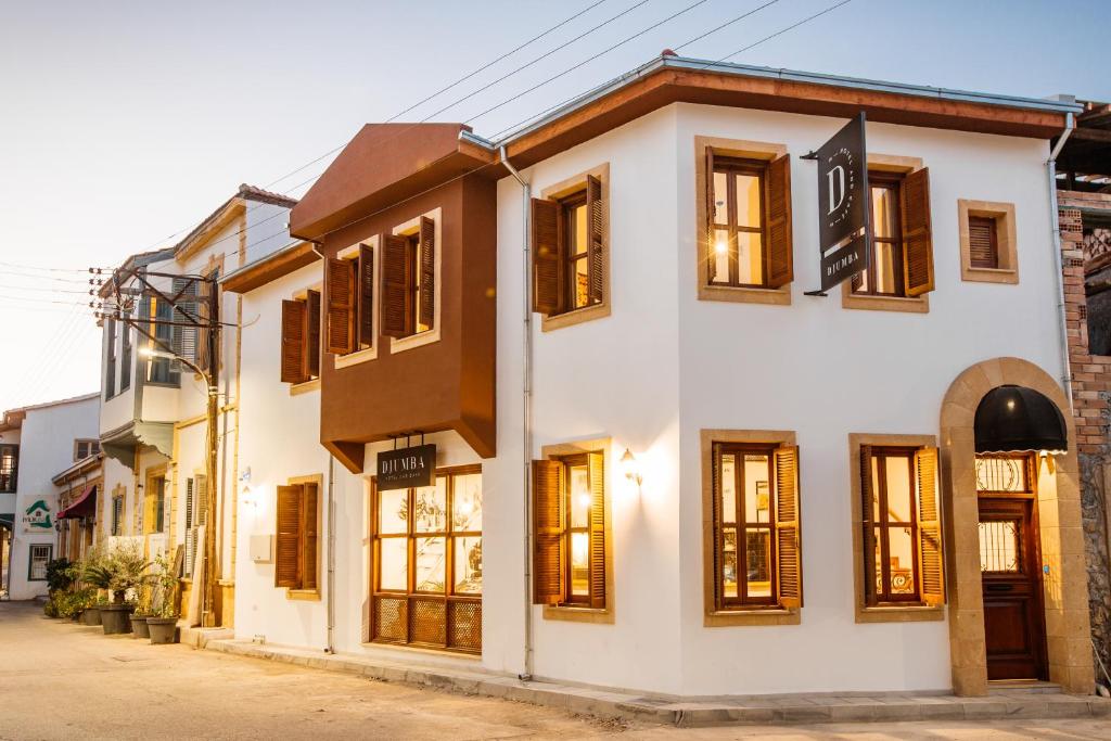 um edifício branco com janelas de madeira numa rua em Djumba Hotel & Cafe em Lefkosa Turk