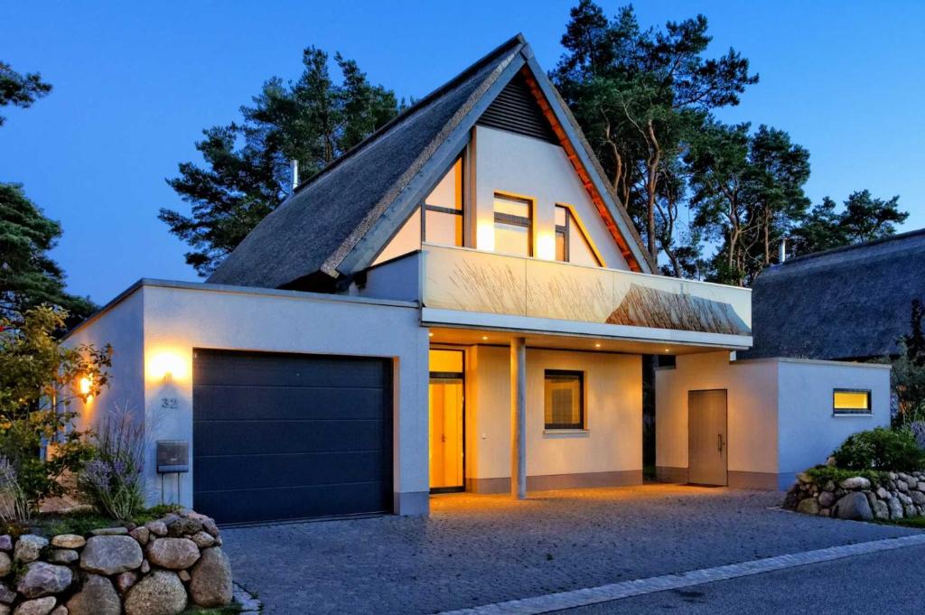 a white house with a garage at dusk at Kapitaensweg 32 in Ostseebad Karlshagen