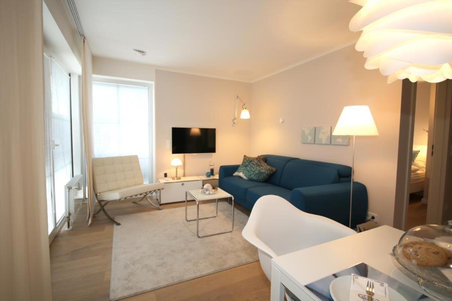ein Wohnzimmer mit einem blauen Sofa und einem TV in der Unterkunft Ferienwohnung Frische Brise in Timmendorfer Strand