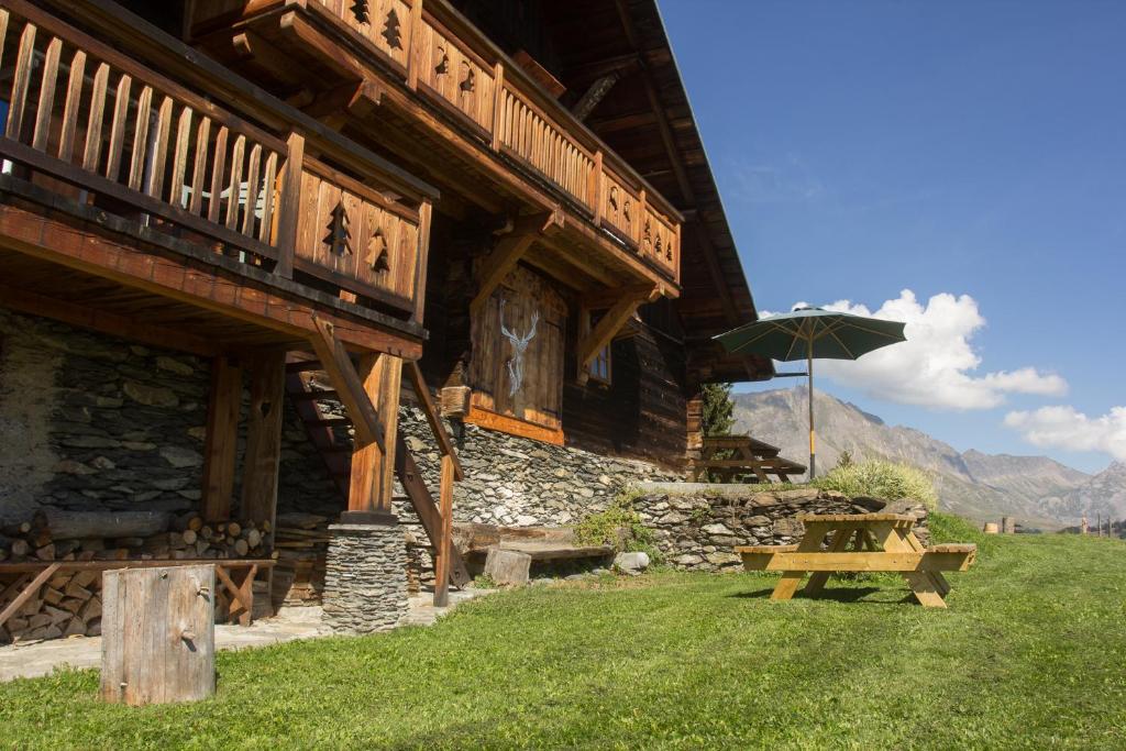 - un bâtiment en bois avec une table de pique-nique et un parasol dans l'établissement Reine des Aravis - chalet isolé, à Flumet