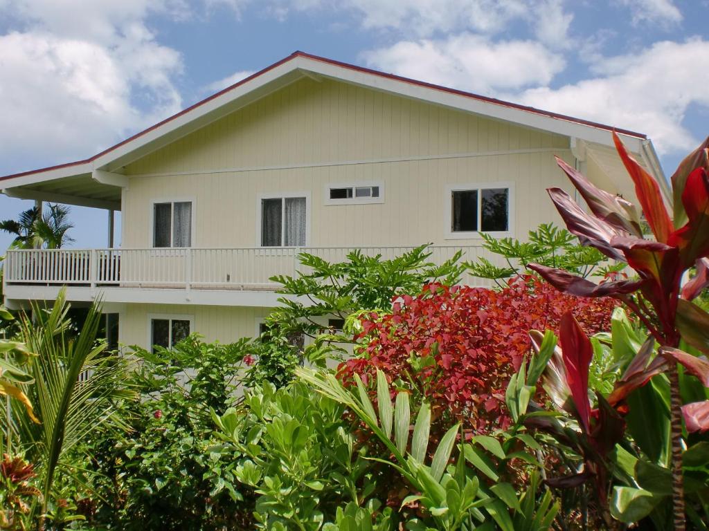 ein weißes Haus hinter einem Garten voller Pflanzen in der Unterkunft Bears' Place Guest House in Kailua-Kona