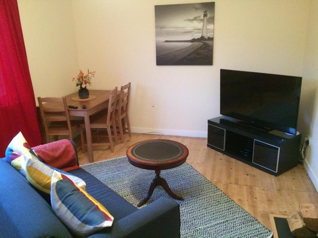 sala de estar con sofá azul y TV en Ardminish House Gigha, en Isle of Gigha