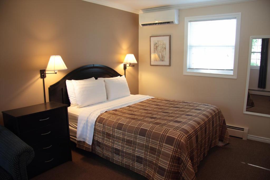 a hotel room with a bed and a window at CARLETON INN & COTTAGES in Bridgetown