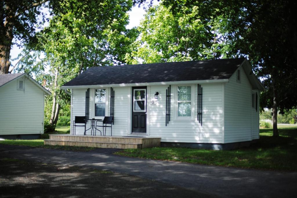 a small white house with a porch and a driveway at CARLETON INN & COTTAGES in Bridgetown