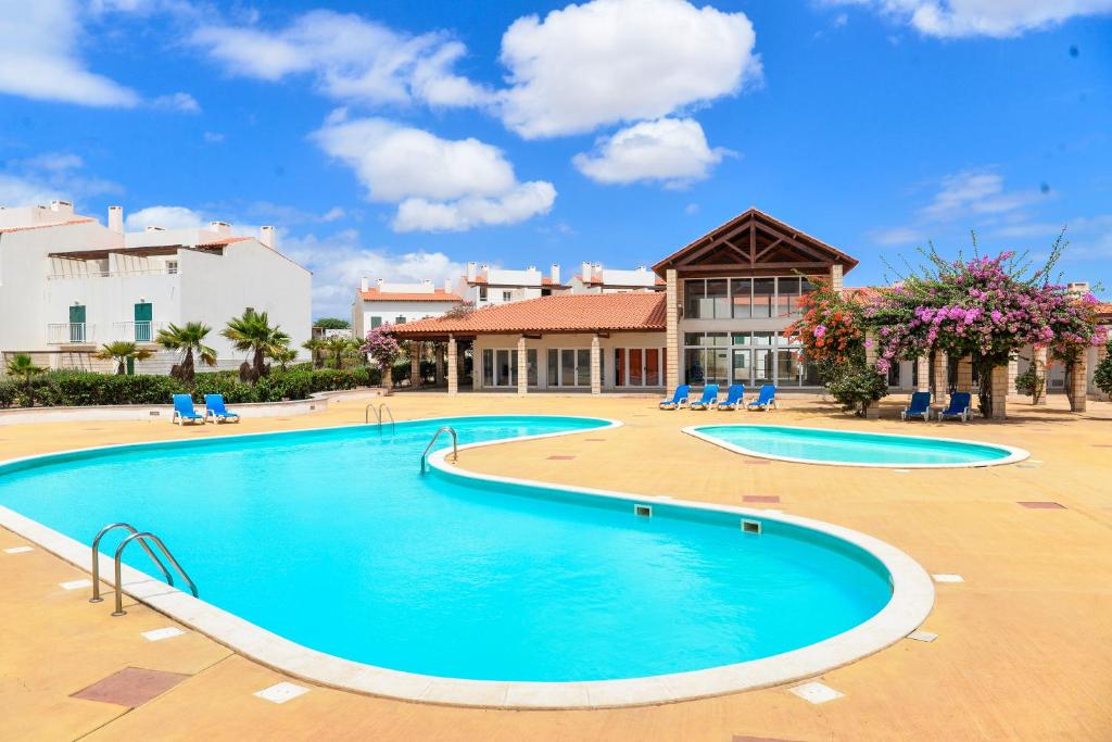 einen Pool in einem Resort mit Stühlen und einem Gebäude in der Unterkunft Guesthouse Le Châtelain in Santa Maria
