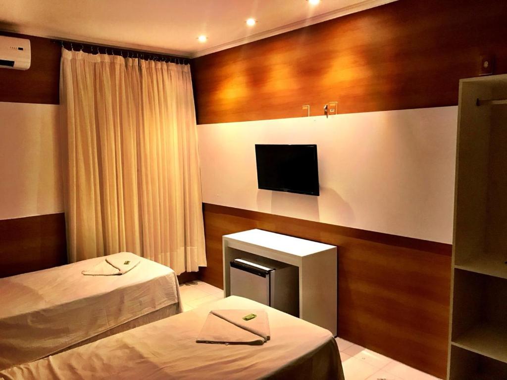 a hotel room with two beds and a television at Hotel Terra do Sal in Mossoró