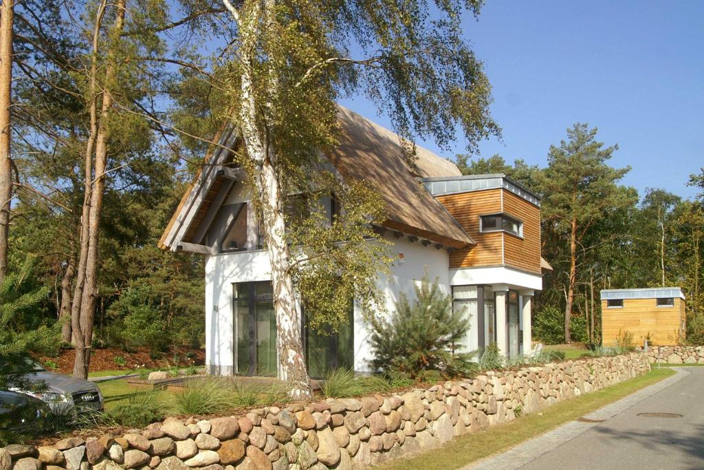 een huis met een stenen muur naast een boom bij Lotsenstieg 15 in Ostseebad Karlshagen