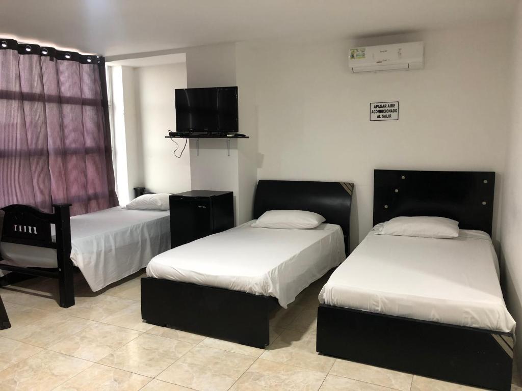 a room with two beds and a flat screen tv at Hostal Central Beach in San Andrés